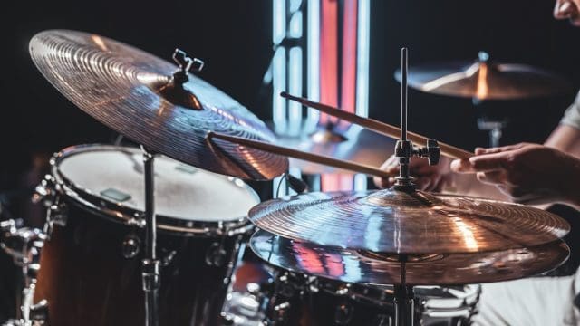 The drummer plays with beautiful lighting on a blurred background.