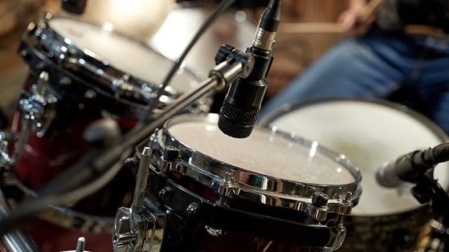 musical instruments and entertainment concept - drums and microphone at music studio