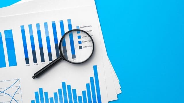 Business graphs and magnifying glass on table, close up