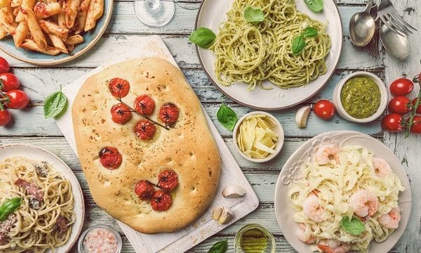 Concepts of Italian food. Table with several plates of pasta with different kinds of sauce and focaccia bread, top view.