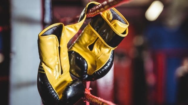 Pair of yellow boxing gloves hanging off the boxing ring
