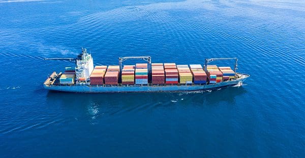 Container cargo ship full loaded, import export business and logistics, aerial view. Water transport, international freight shipping, commercial trade and transportation in the open sea