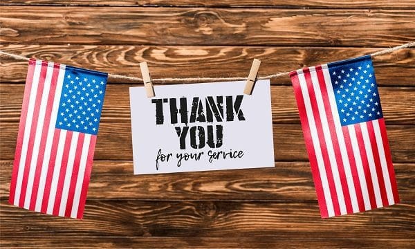 card for veterans day hanging on string with pins and american flags on wooden background