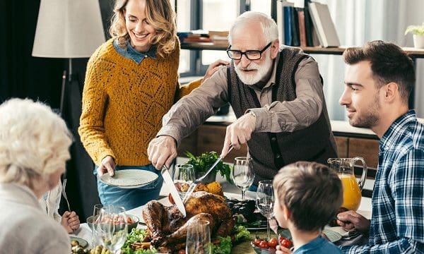 grandfather cutting turkey for family on thanksgiving dinner