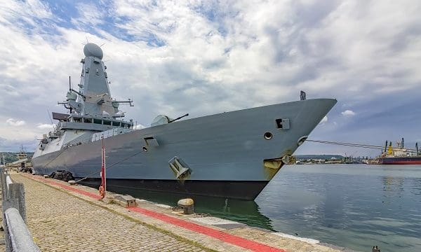 Military navy ship in port. Military sea landscape with cloudy sky at sunset