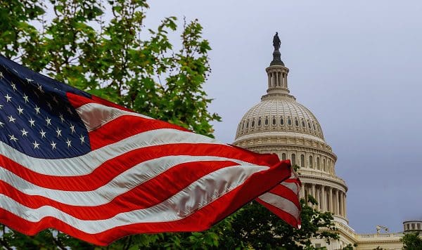 The US Capitol building with a waving American flag superimposed on the sky Capitol Hill in Washington DC
