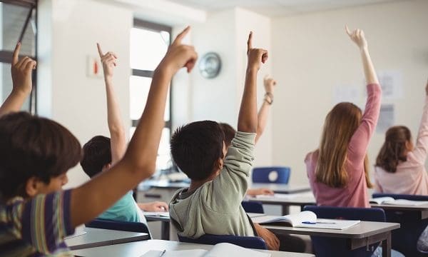 School kids raising hand in classroom at school