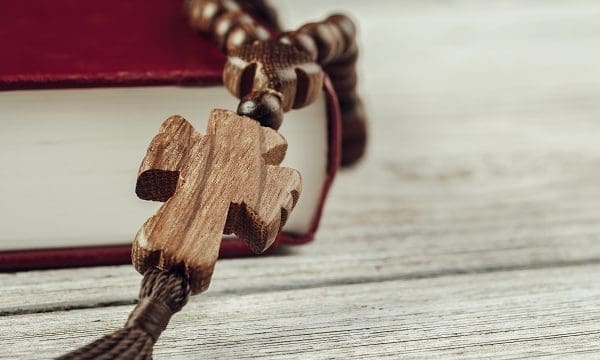 Bible and a crucifix on an old wooden table. Religion concept.