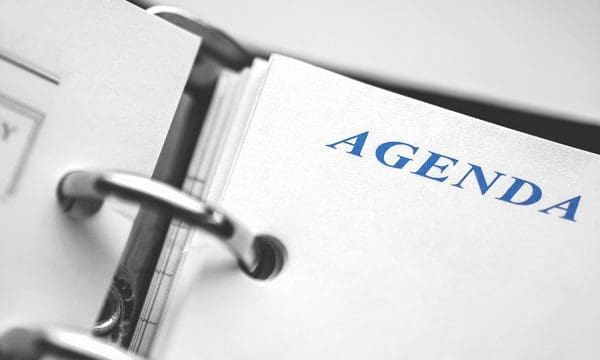 Daily agenda paper planner closeup. Black and white picture with blue word Agenda in focus