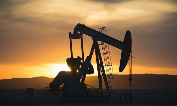 A pumpjack at an oil drilling site at sunset.