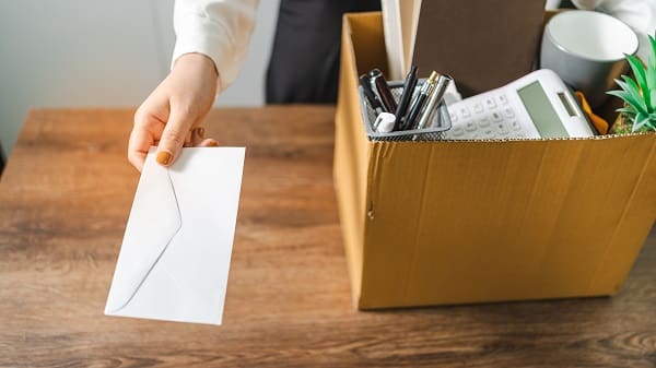 Business woman sending resignation letter and packing Stuff Resign Depress or carrying business cardboard box by desk in office. Change of job or fired from company.
