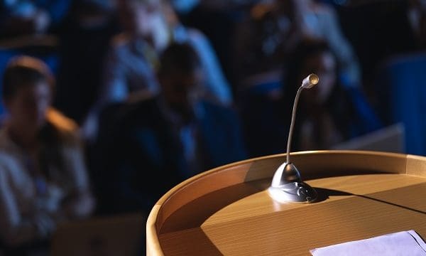 Close up of podium with speaker in auditorium
