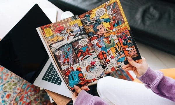 Person reading comic book at home in living room.