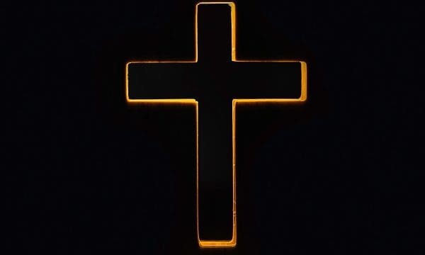 Silhouette of christian cross, lights, bokeh on black background. Copy space. Faith symbol. Church worship, salvation concept. Faith symbol in Jesus Christ. Holy cross for Easter day. Christianity.