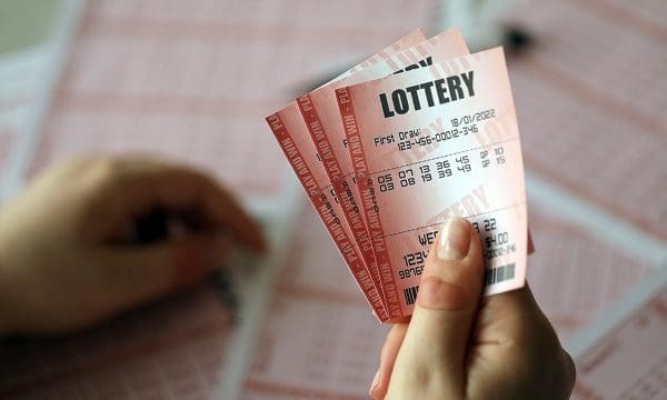 Filling out a lottery ticket. A young woman holds the lottery ticket with complete row of numbers on the lottery blank sheets background. Gambling concept