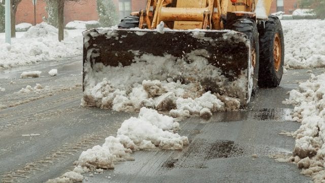 Snowplow removing snow from city road Snow-plow tractor