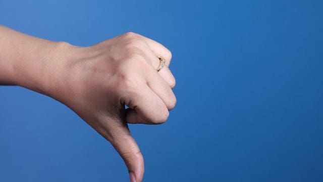 hand showing thumb down sign on blue background