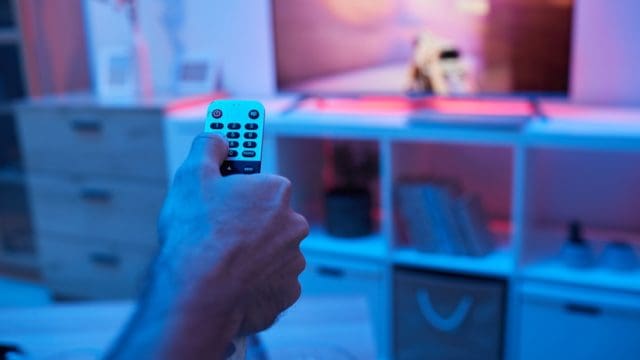 Close-up of man using remote control and changing the channels during watching TV