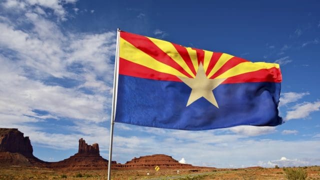 Arizona Flag on Wind. Arizona State Desert Landscape Near Monuments Valley, AZ, United States.
