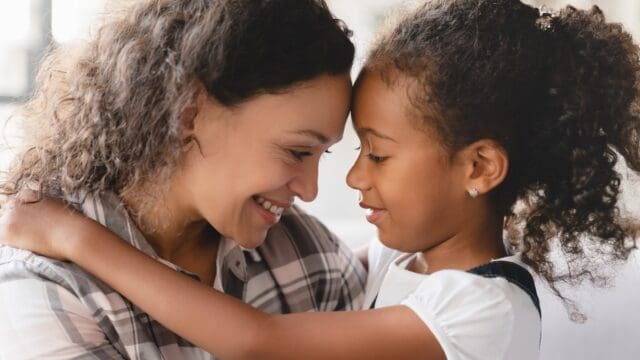African-american mother and small little young preteen daughter hugging embracing with eyes closed sharing love and care. Motherhood. Happy Mother`s day!