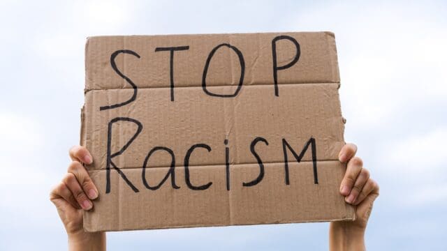 banner in hand stop racism against the sky