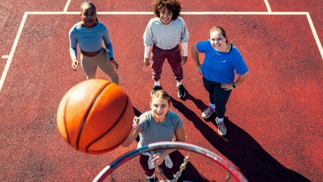 Portait of diverse group of young woman having fun playing basketball outdoors.