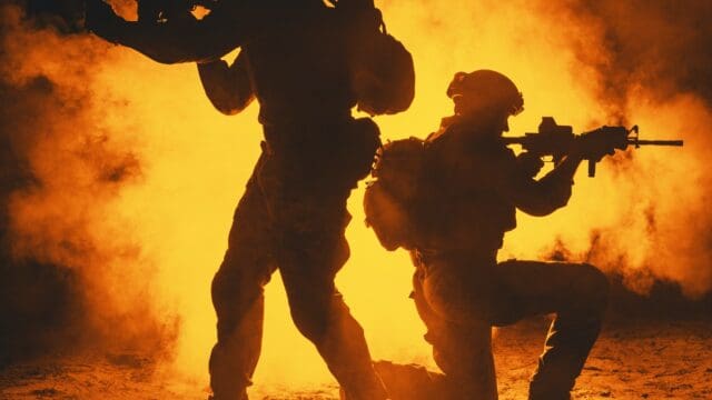 Pair of army soldiers attacking in the smoke. Backlit silhouette, toned image. Army storm concept
