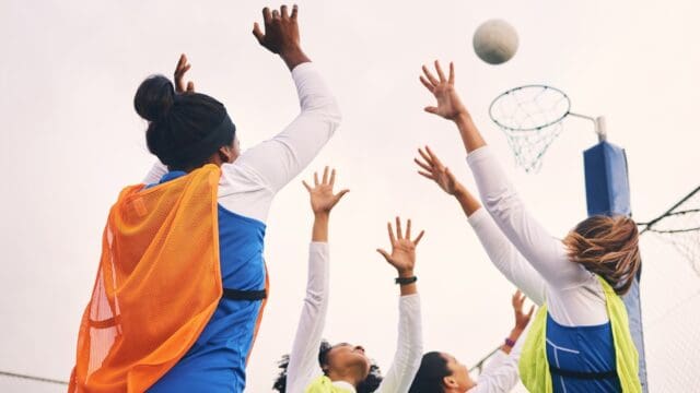 Netball, goal shooting and fitness of a girl athlete group on an outdoor sports court. Aim, sport g.
